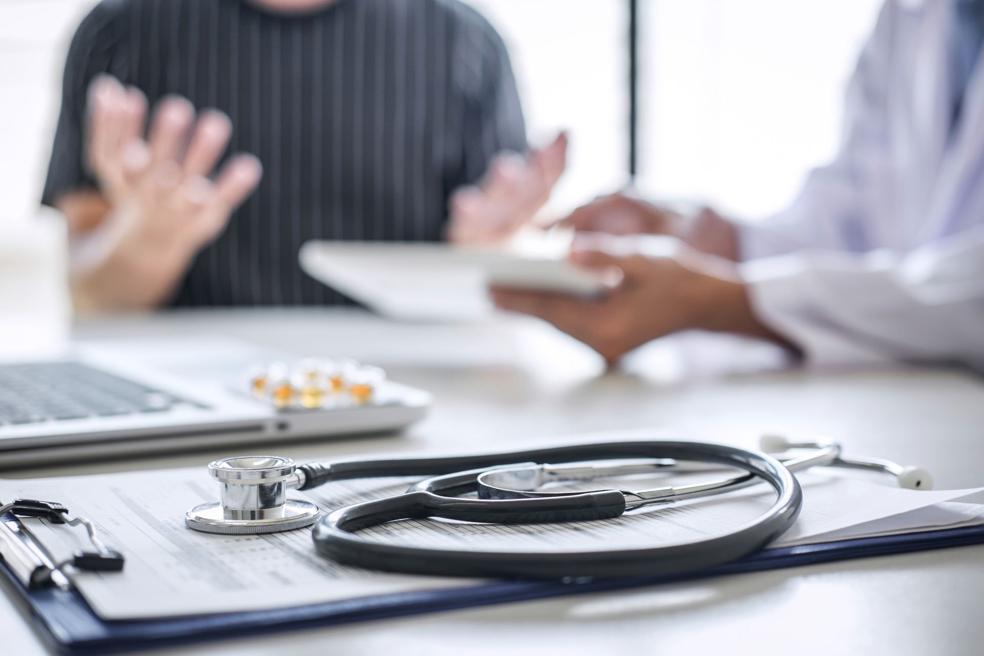 Doctor and patient in a clinic, with a stethoscope on a desk during a consultation