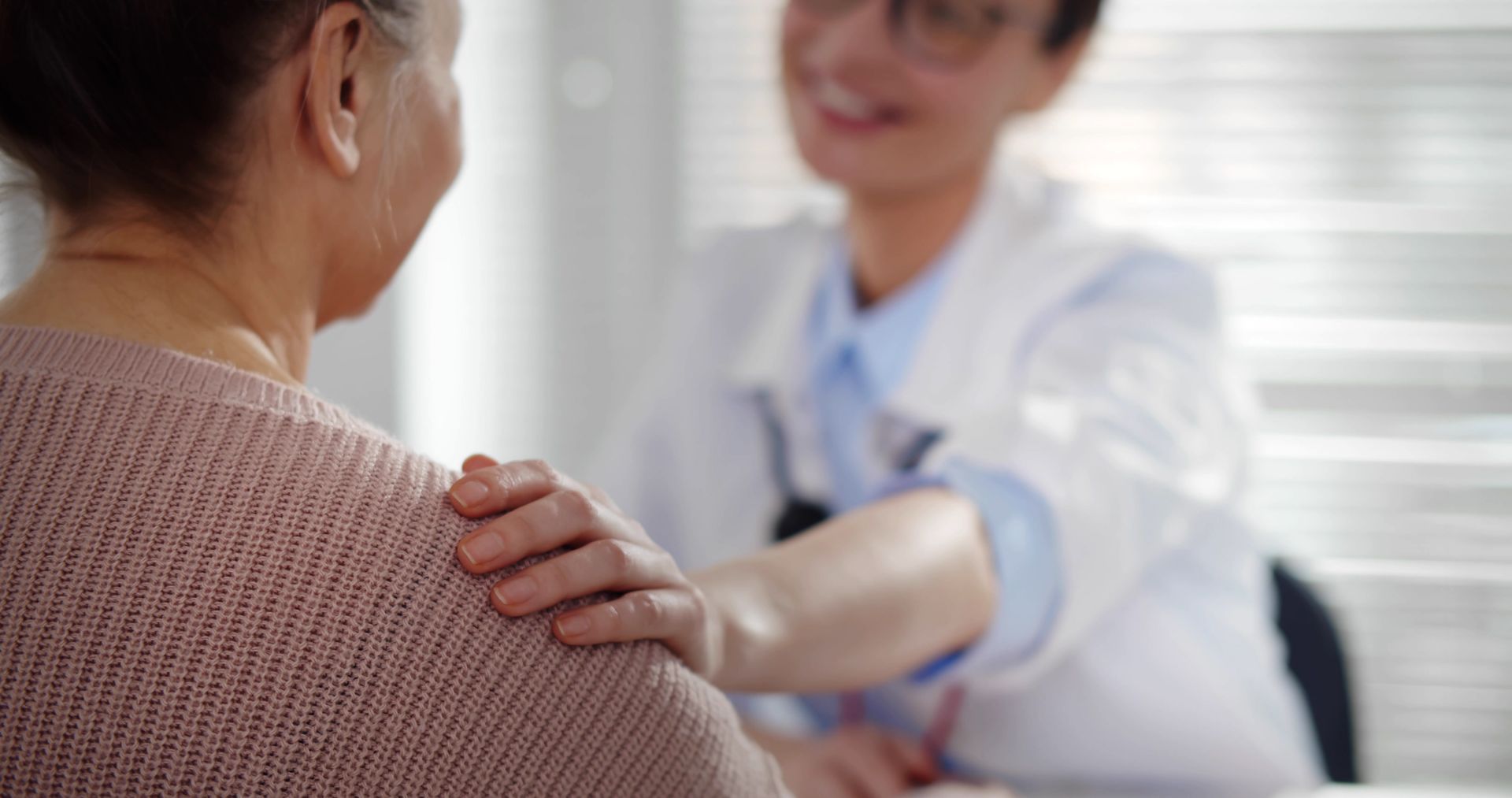 Patient speaking with a doctor who is placing a reassuring hand on their shoulder in a clinic office.