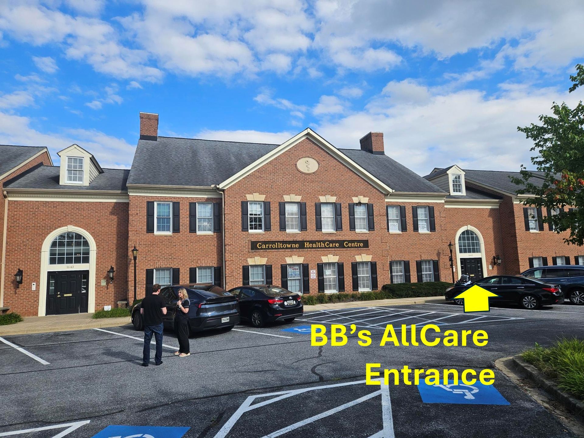 Brick office building with parked cars beside a paved lot under a clear blue sky