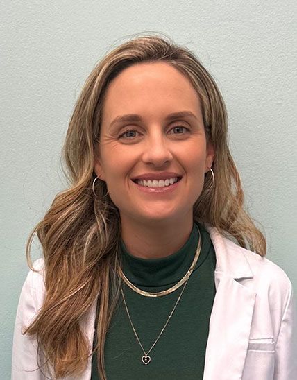 Smiling professional in white coat and green top, with layered gold necklaces, on a white background Smiling professional in white coat and green top, with layered gold necklaces, on a white background