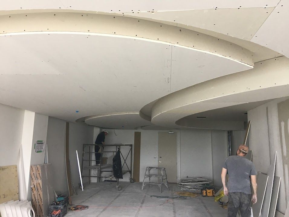 Interior under construction with curved ceiling, scaffolding, and a worker standing on the right
