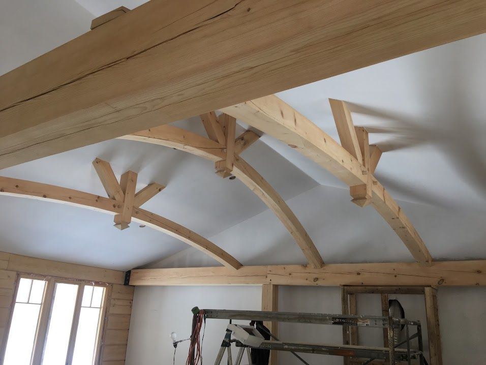 Wooden beams and braces on a white ceiling with curved support beams.