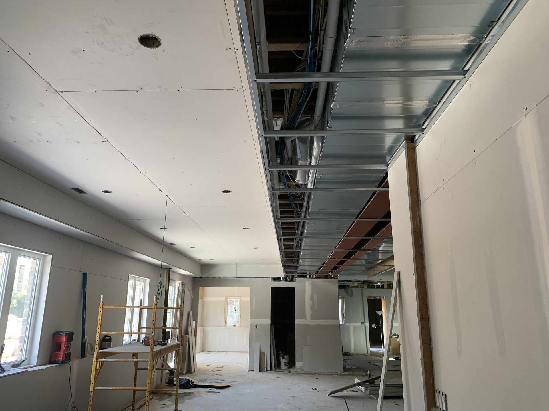 Interior room under construction, with exposed ceiling frame and drywall partially installed.