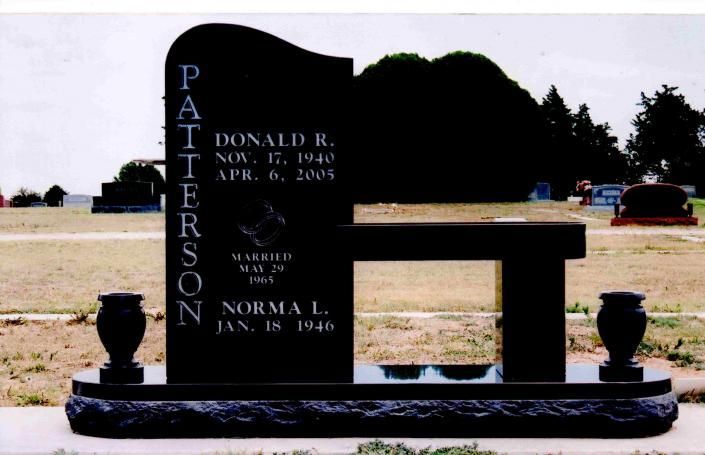 Black granite memorial gravestone in a cemetery with engraved name and dates.