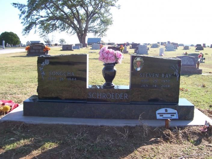 Two gravestone memorial with flowers in a cemetery on a sunny day