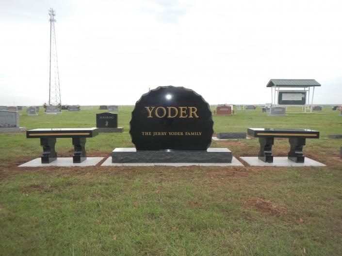 Yoder welcome sign in a grassy roadside area, flanked by benches under an overcast sky