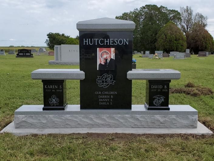 Black memorial headstone with photo and two matching vases in a grassy cemetery.