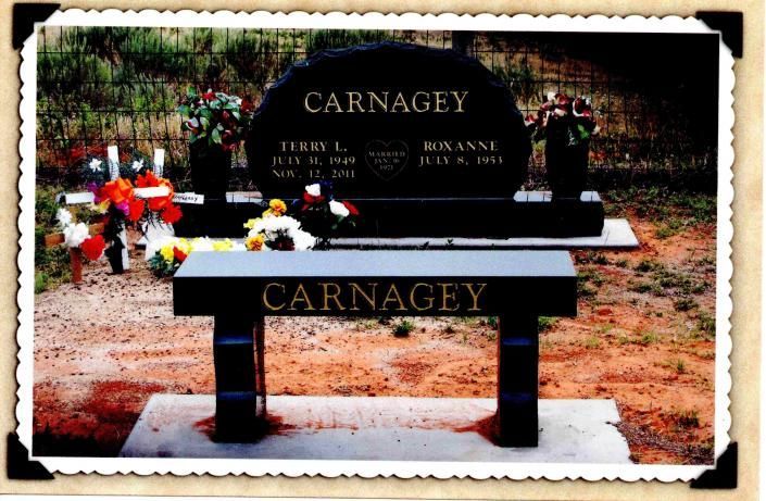 Black granite Carnagey family gravestone with flowers in a cemetery