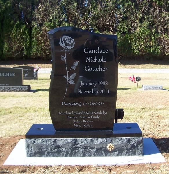 Black granite memorial headstone with a rose engraving in a grassy cemetery