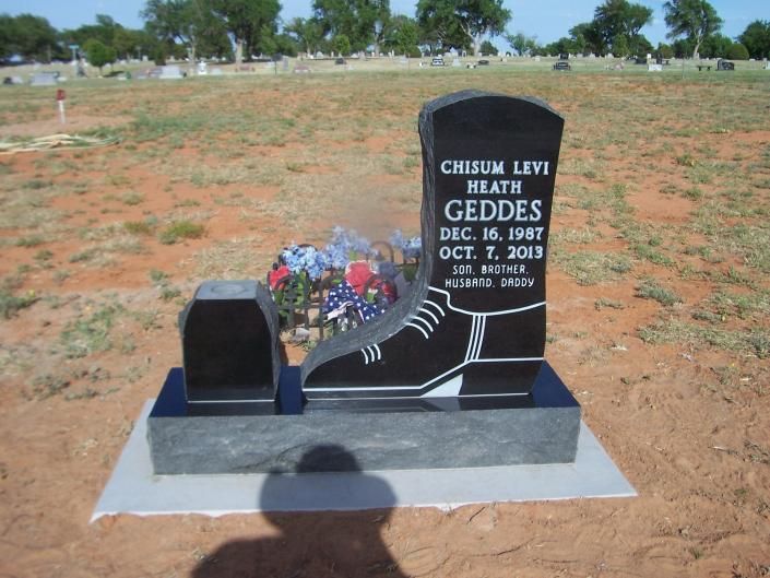 Black granite gravestone with flowers in a cemetery under a sunny sky