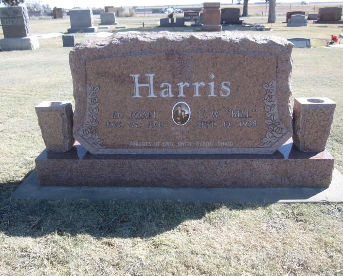 Brown granite Harris gravestone in a cemetery with grass and other headstones in the background