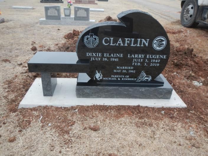 Black granite memorial bench gravestone with engraved names on a white base in a cemetery