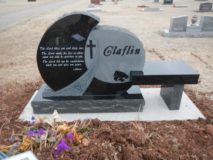 Black and gray gravestone with “Claffin,” a bench, and flowers in a cemetery.