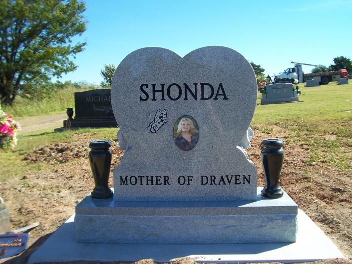 Gravestone reading “Shonda” and “Mother of Draven” in a cemetery with flowers nearby.