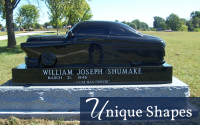 Black custom car-shaped gravestone in a green cemetery, labeled William Joseph Shumake.