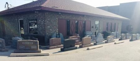 Small brick storefront with outdoor seating and tables along a sunny sidewalk