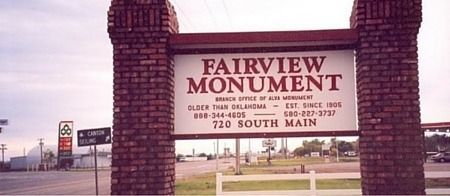 Fairview Monument sign at a roadside entrance, with brick columns and a parked car in the background