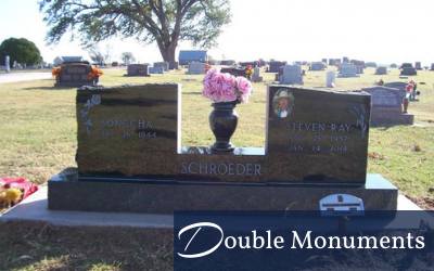 Double headstone monument with pink flowers in a cemetery, “Double Monuments” sign at bottom.