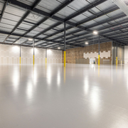 Empty industrial warehouse with polished concrete floor, metal ceiling, and yellow support columns