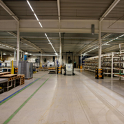 Empty factory interior with conveyor belts, machinery, and overhead lighting in a large warehouse