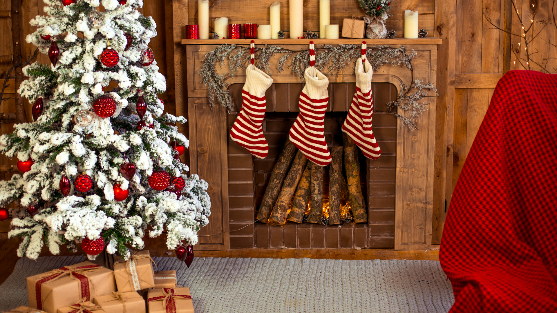 Christmas scene: snowy tree with red ornaments, fireplace with stockings, wrapped gifts.