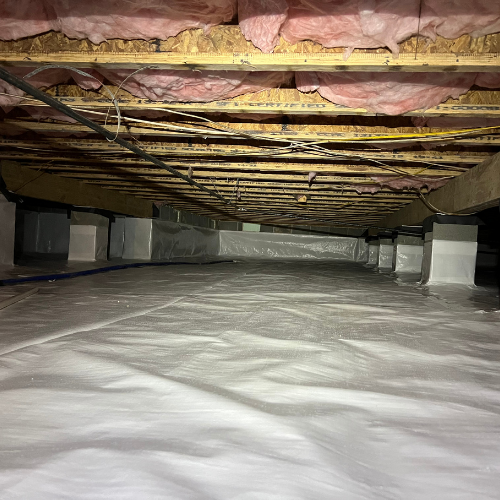 Crawlspace with white vapor barrier, supporting piers, wooden joists, and pink insulation above.