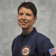 a woman in a karate uniform is smiling for the camera .