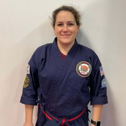 a woman in a blue karate uniform is smiling for the camera .
