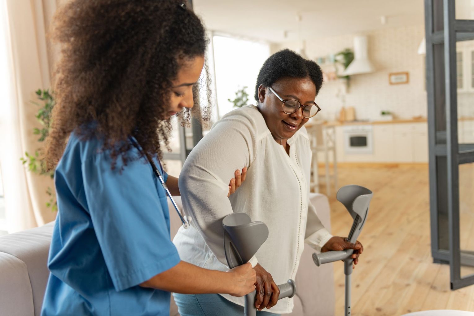 Two people using crutches in a bright home interior