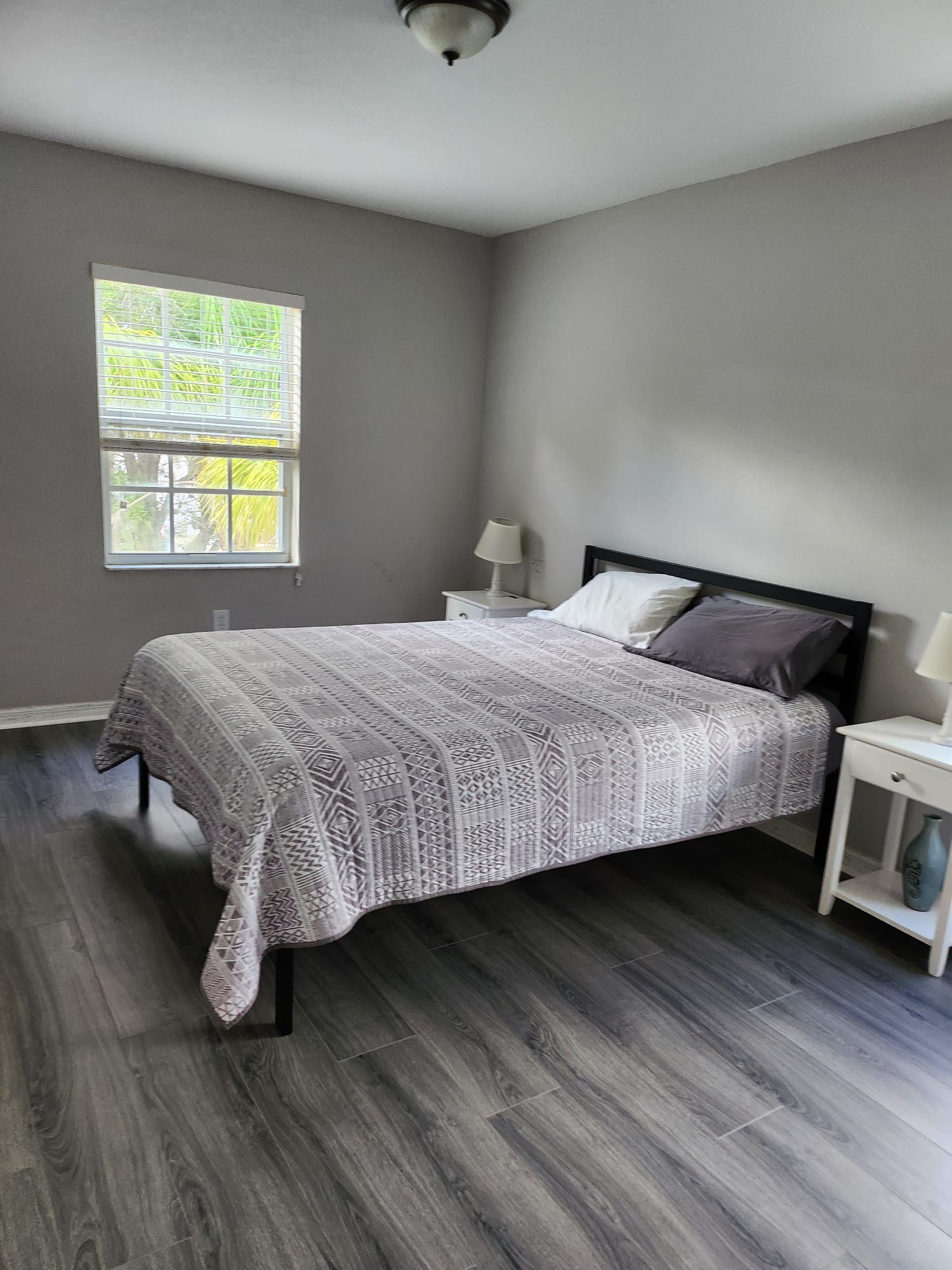 A bedroom with a bed , two nightstands , and a window.