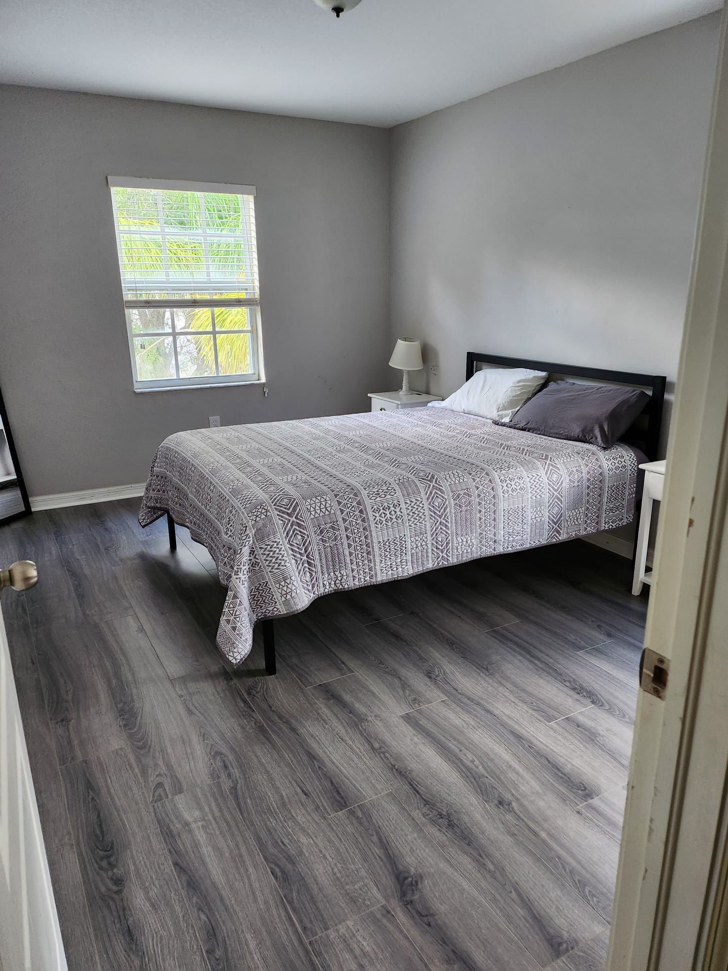 A bedroom with a bed , nightstand , and window.