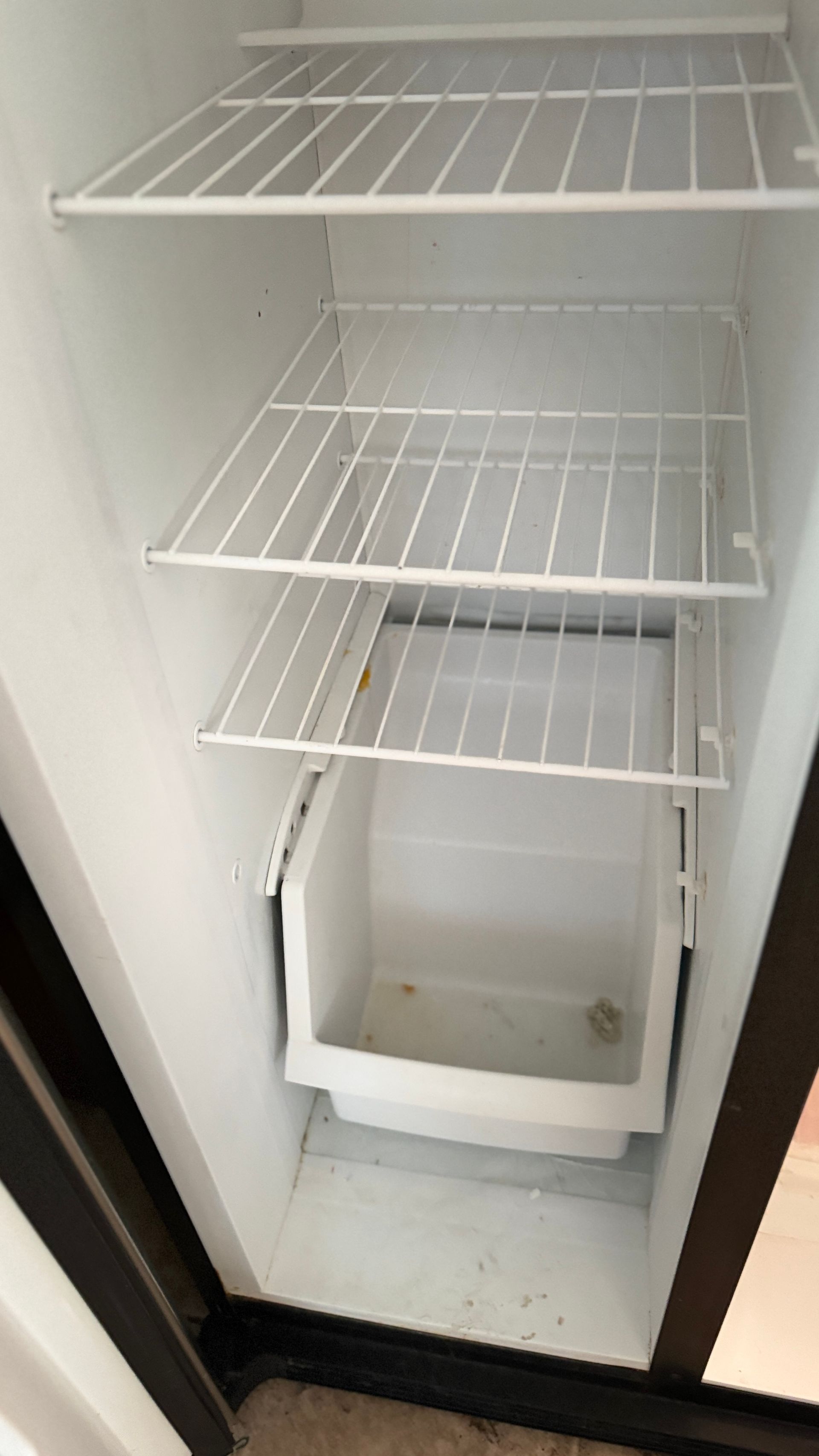 An empty refrigerator with shelves and an ice cube tray