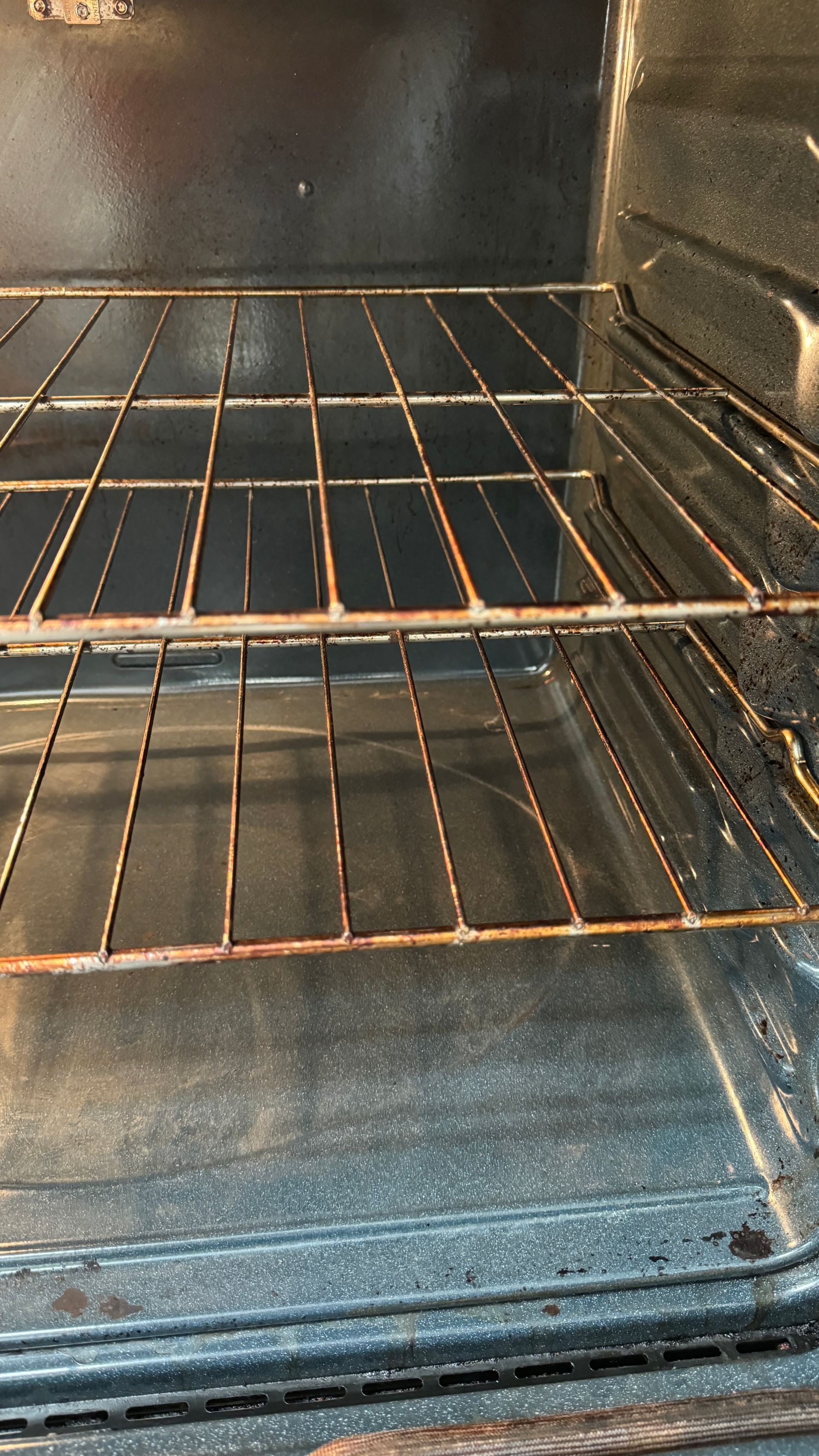 A close up of an empty oven with a dirty rack.