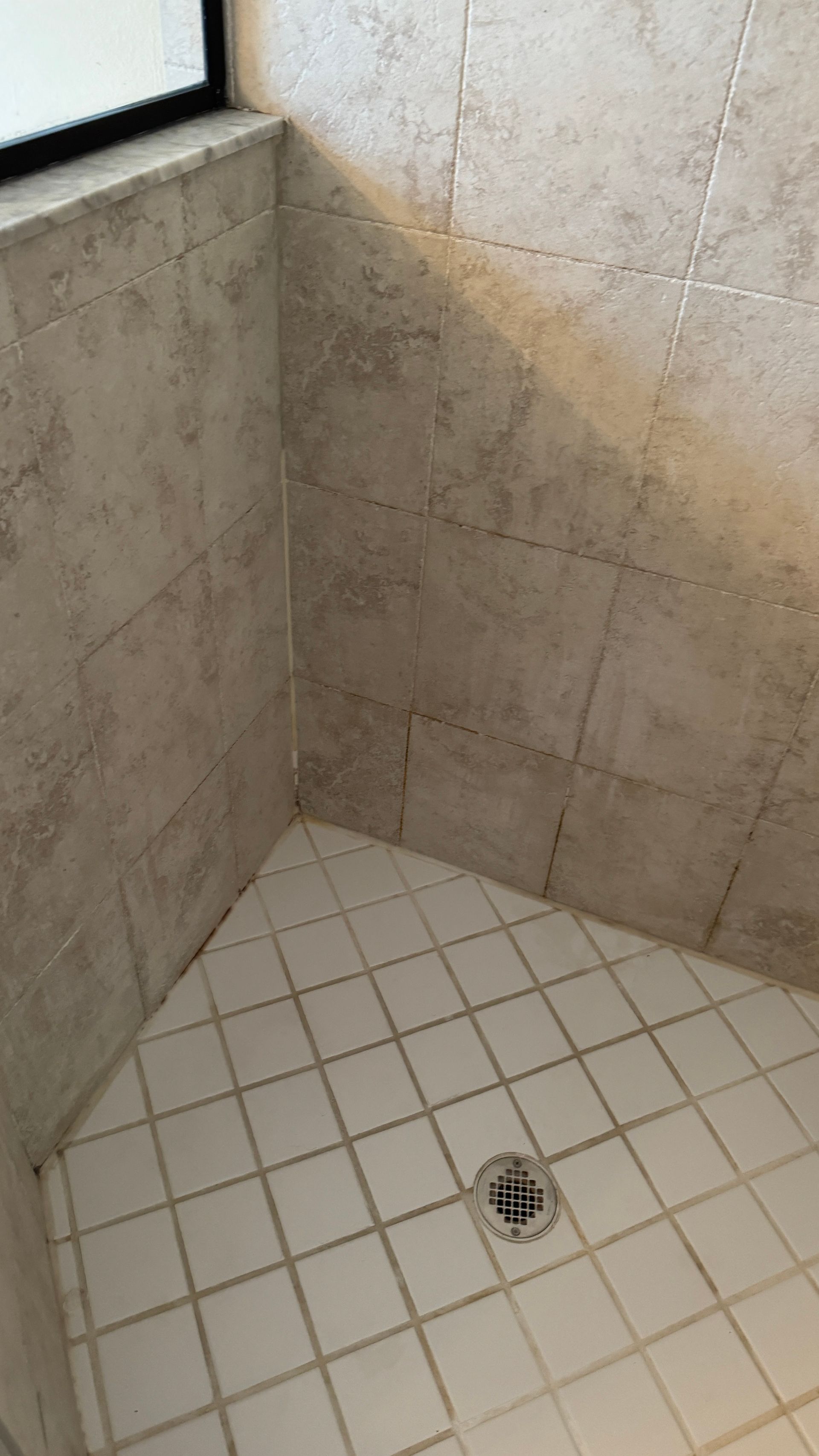 A shower stall with white tiles and a window.