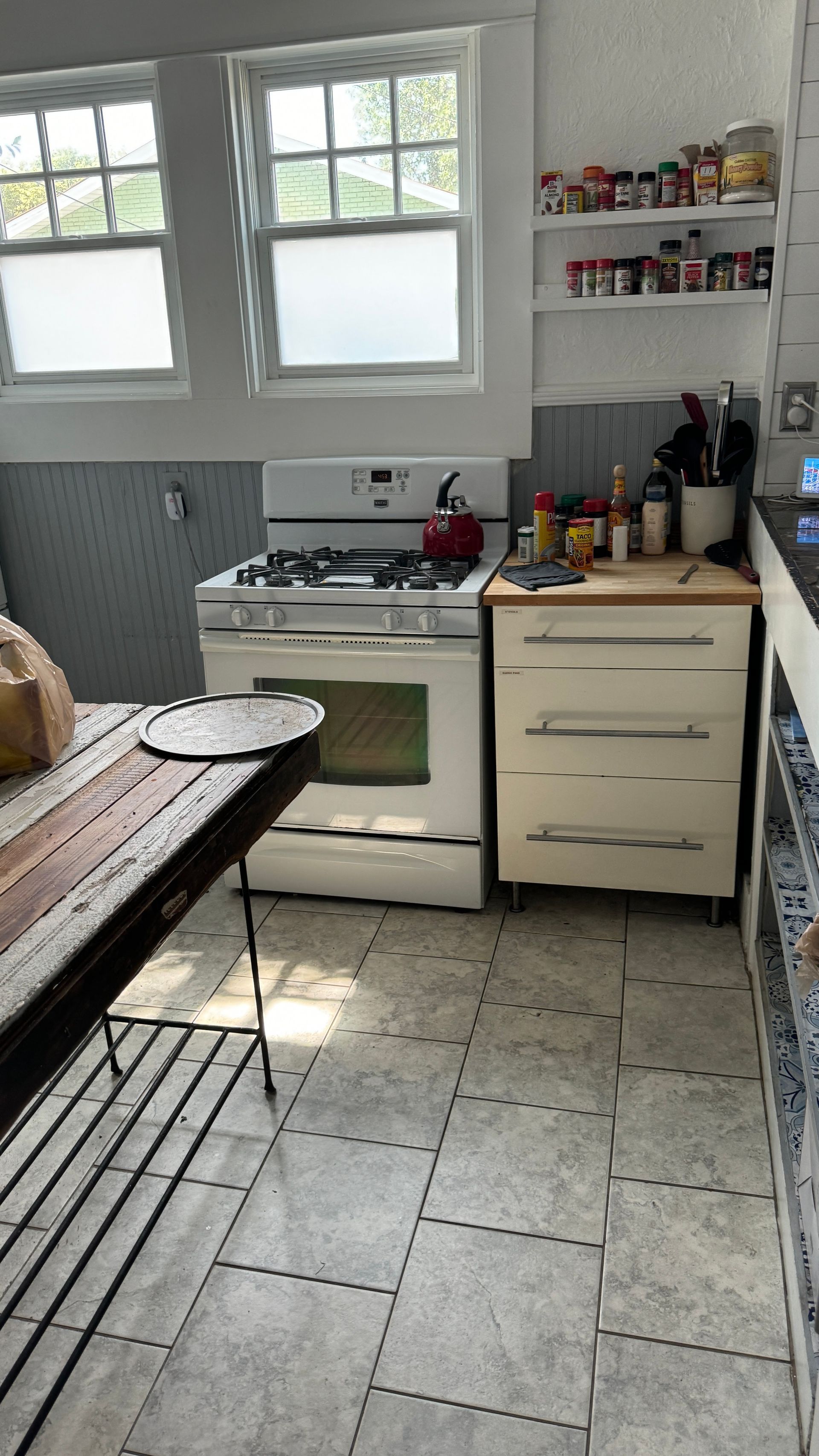 A kitchen with a stove , oven , cabinets and a table.