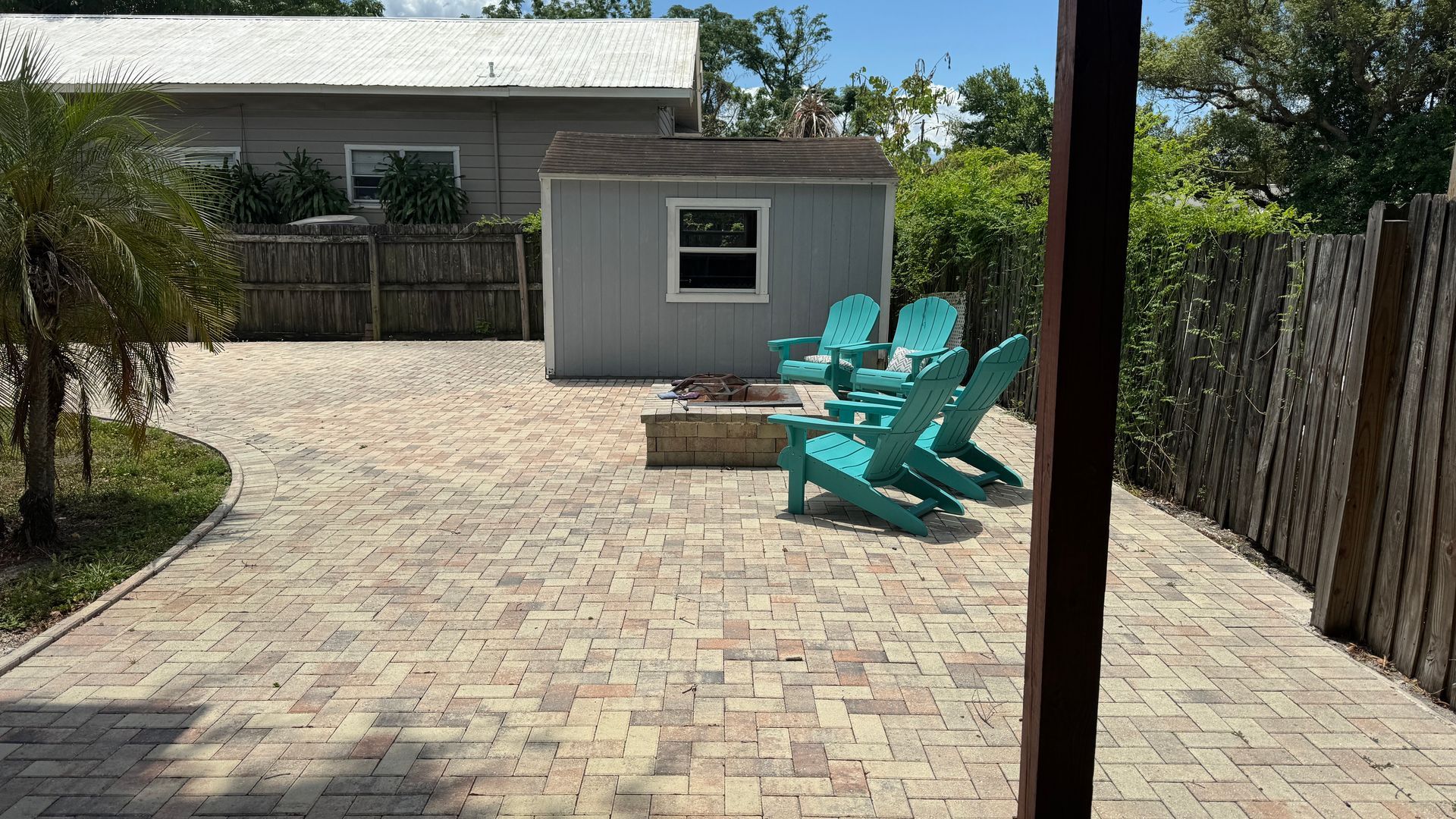 A patio with blue chairs and a fire pit in front of a house.