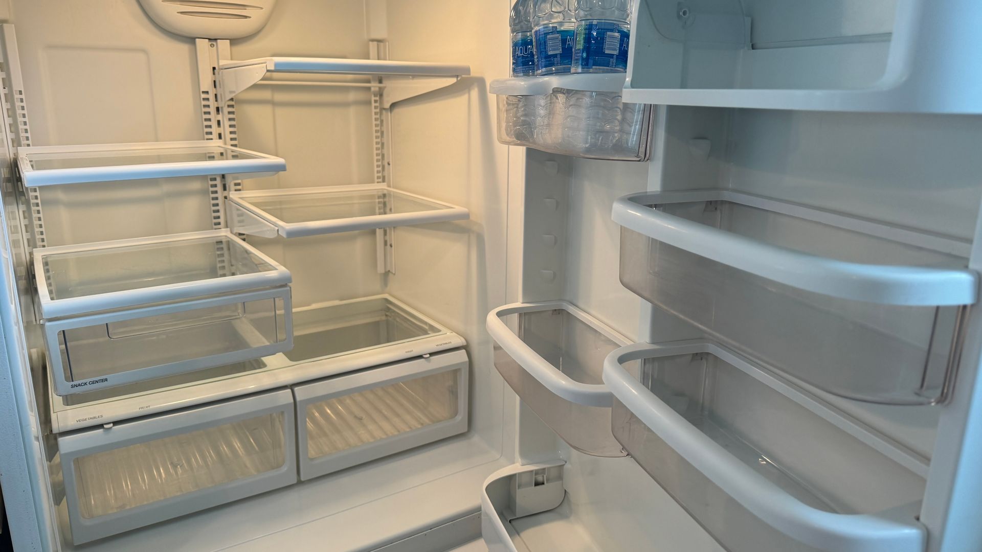 The inside of an empty refrigerator with shelves and drawers.