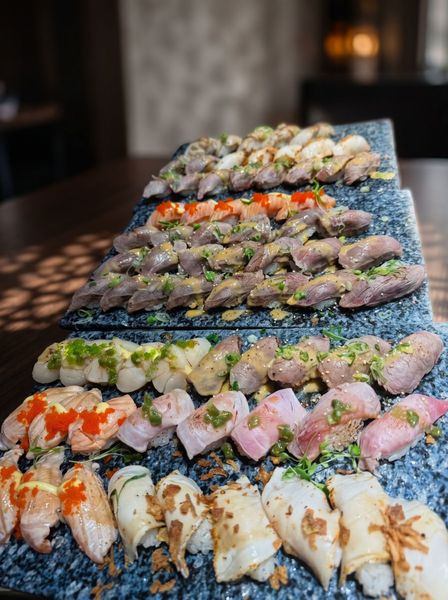 Assorted sushi rolls arranged on tiered black trays on a table