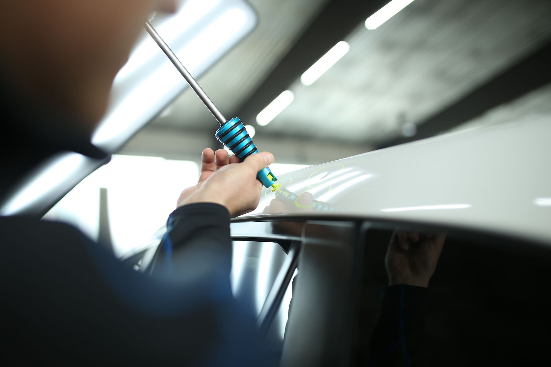 A man is working on a car with a hammer.