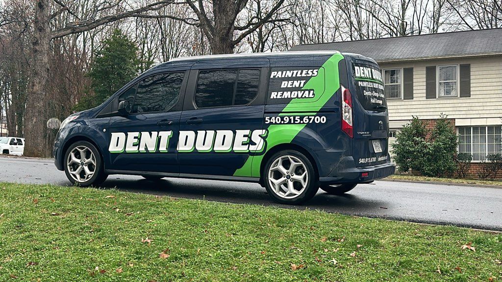 A dent dudes van is parked in front of a house.