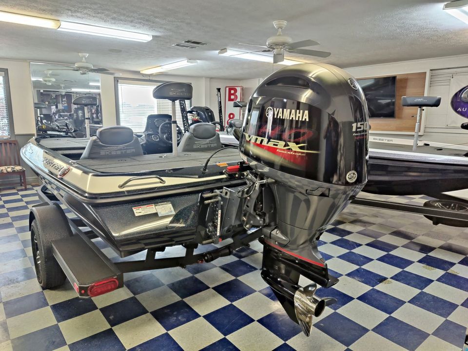 A boat with a yamaha outboard motor is sitting in a room with a checkered floor.