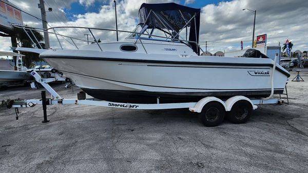 A white boat is parked on a trailer in a parking lot.