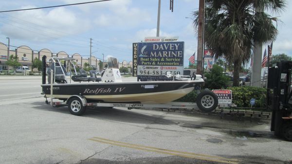 A boat is parked on a trailer in front of a davey marine sign.