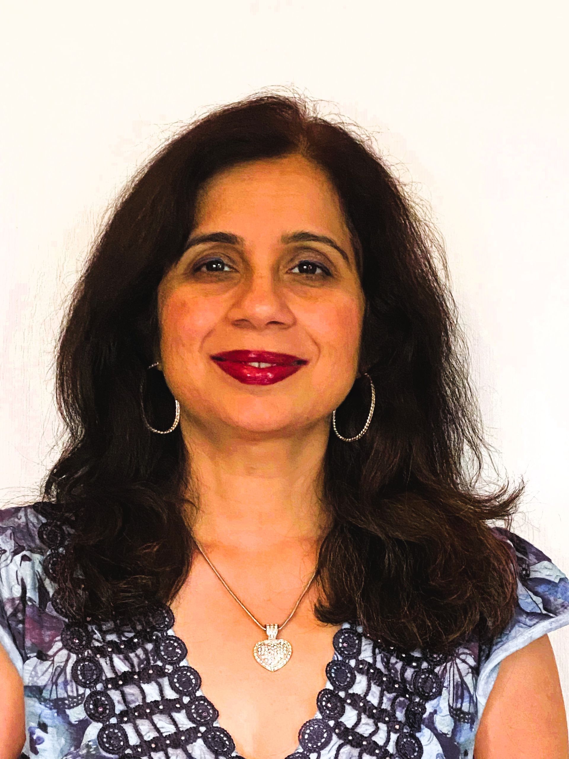 A woman wearing a necklace and earrings is smiling for the camera.
