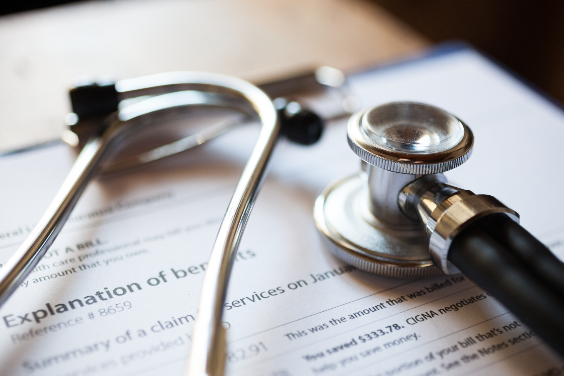A metal stethoscope rests on top of a medical Explanation of Benefits document.