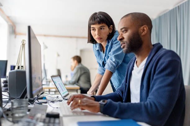 A man and a woman are looking at a laptop computer.