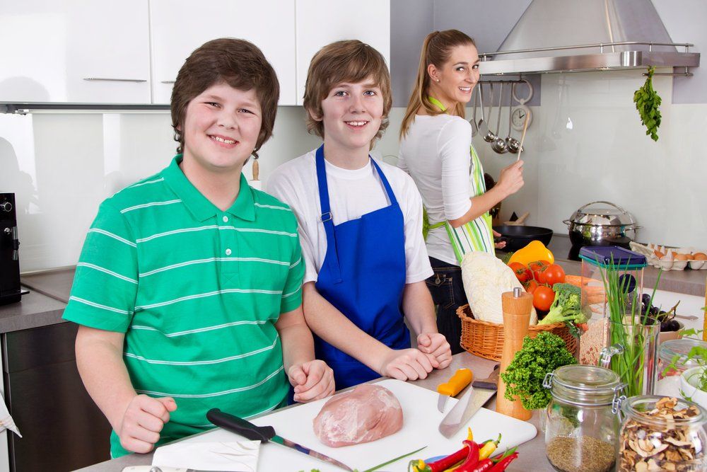 Eine Gruppe junger Leute steht in einer Küche und bereitet Essen zu.