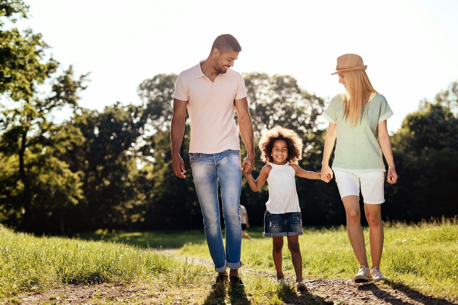 A smiling family laughing together outdoors in the warm glow of the setting sun.