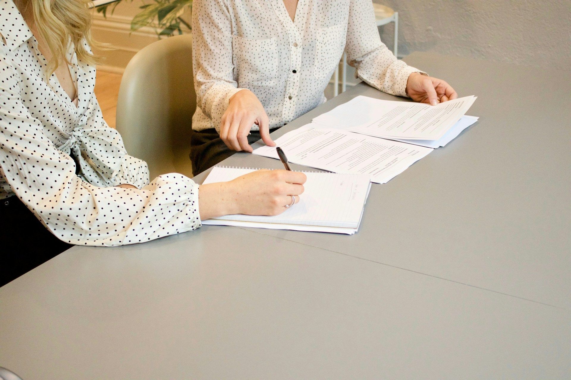 Two people reviewing documents at a table, one pointing with a pen.