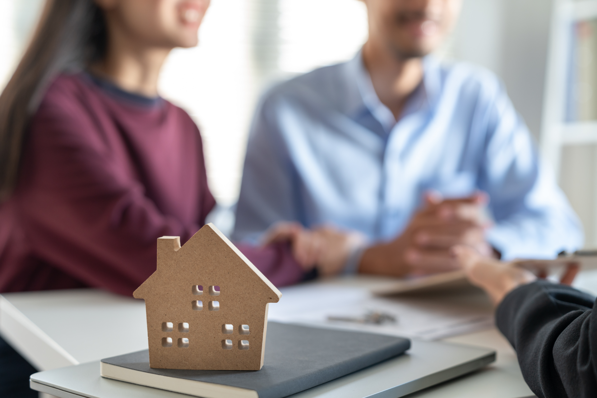 House model on table during meeting with two blurred people in the background
